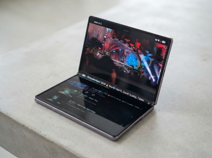 Smartphone pliable ouvert affichant une vidéo sur une surface en béton.
