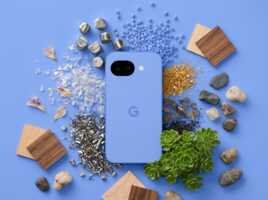 Un smartphone Google Pixel bleu entouré de matériaux naturels et industriels, éclairage diffus, vue de dessus.