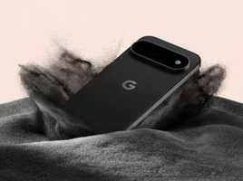 Smartphone Google Pixel noir posé sur un tas de sable noir.