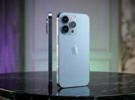 Un iPhone bleu photographié sur une table en marbre, éclairage de studio, style photographie produit.