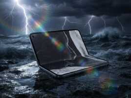 Smartphone pliable posé sur des rochers face à une mer agitée sous un orage avec des reflets lumineux.