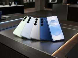 Quatre smartphones Samsung de couleurs différentes alignés sur un présentoir en magasin.
